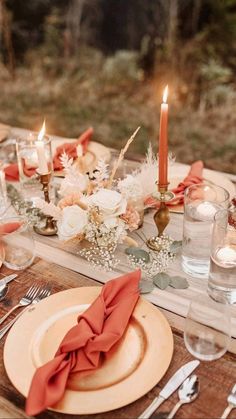 the table is set with candles, plates and napkins