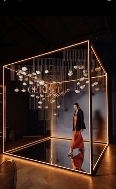 a woman standing in front of a glass display case with lights hanging from the ceiling