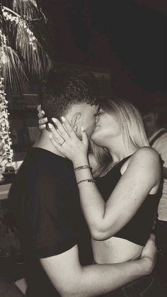 black and white photograph of a man kissing a woman's face with fireworks in the background