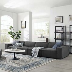 a living room filled with furniture and a large rug on top of a hard wood floor