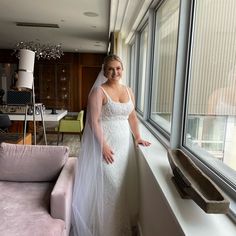 a woman in a wedding dress leaning against a window sill with her hand on her hip