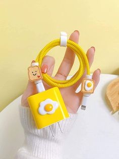 a hand holding a yellow cable with an egg on it and two plugs attached to it