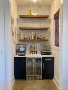 an open kitchen area with shelves, cabinets and wine glasses on the counter top in front of it