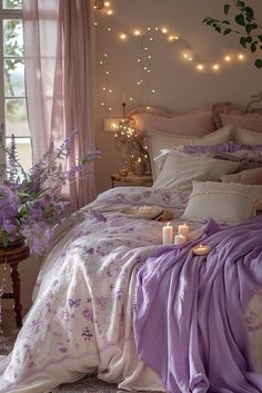 there is a bed with purple sheets and candles in the room, along with flowers