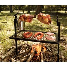 two sausages being cooked on a grill over a campfire in the woods with hot dog buns