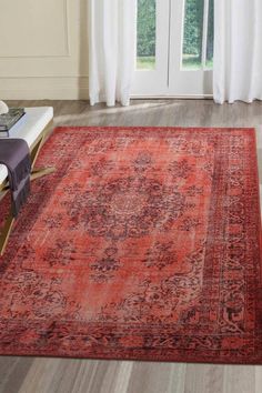 a large red rug with an ornate design on the floor in front of a window