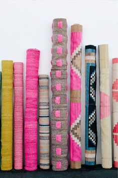 a bunch of different colored rugs are lined up on the wall with each other