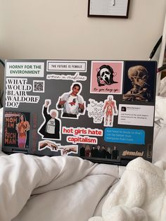 an open laptop computer sitting on top of a bed covered in stickers and paper