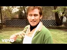 a man holding a banana in his right hand while standing on top of a grass covered field