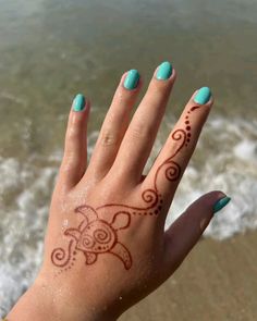 a woman's hand with a tattoo on it and the ocean in the background