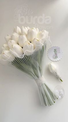 a bouquet of white tulips with a tag attached to the stems on a table