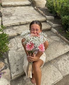 a woman sitting on steps with flowers in her hand