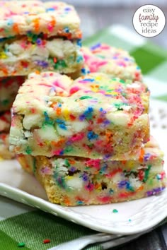 colorful sprinkles are on top of white cake bars stacked on a plate