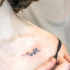 a woman with a small tattoo on her chest holding onto her arm and looking at the camera