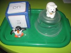 a plastic penguin and polar bear sitting on a green tray next to an object that says i can't read