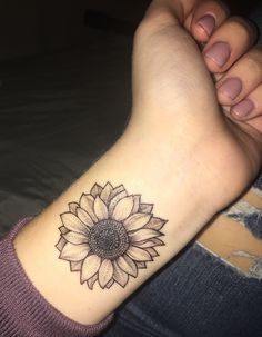 a woman's arm with a sunflower tattoo on the left side of her wrist