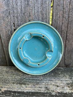 a blue plate sitting on top of a wooden table next to a fence and wood planks