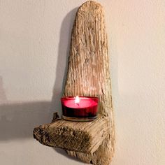 a candle is lit on a piece of driftwood that has been placed on the wall