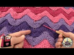 someone crocheting a chevron blanket with a knitting needle in front of the camera