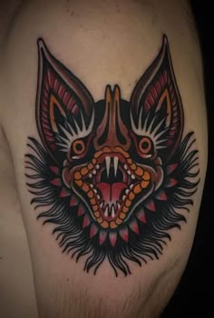 a bat tattoo on the back of a man's left arm, with an open mouth