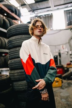 a man standing next to some tires in a garage with one hand on his hip