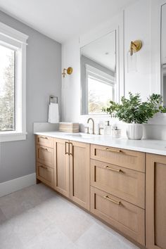 a large bathroom with two sinks, mirrors and plants in vases on the counter