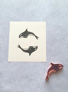 a stamp with two dolphins on it next to a piece of paper that has the shape of a dolphin