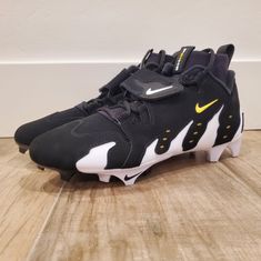 a pair of black and yellow nike shoes on a wooden floor in front of a white wall