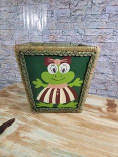 a basket with a frog on it sitting on top of a table next to a knife