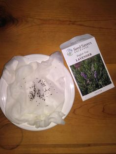 a white plate topped with whipped cream next to a packet of lavender seeds on top of a wooden table