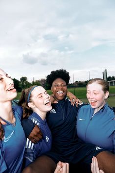 a group of young women standing next to each other on top of a soccer field