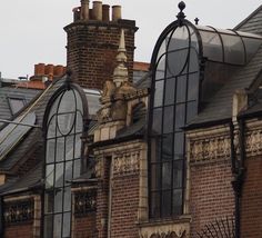 an old brick building with many windows and statues on the roof