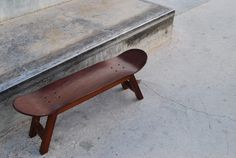 a skateboard sitting on top of a wooden bench next to some stairs and cement steps