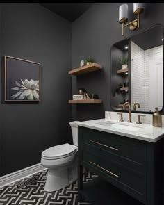 a black and white bathroom with gold accents on the vanity, toilet and mirror above it