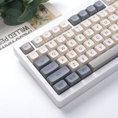 a computer keyboard sitting on top of a white table next to a potted plant