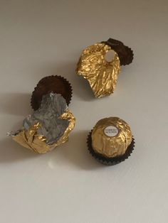 three chocolates wrapped in foil sitting on top of a white table next to each other