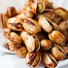 a pile of pistachio nuts sitting on top of a white paper bag filled with them