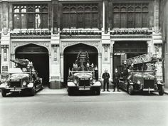 three fire trucks parked in front of a building with two men standing next to them