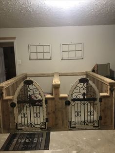 two wooden gates with wrought iron on them in front of a white wall and rug