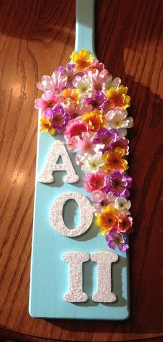 a wooden spoon with flowers on it and the word aoi spelled in white letters