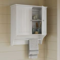 a white cabinet mounted to the side of a wall next to a towel rack and sink