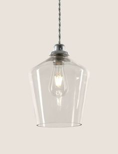 a clear glass light hanging from a ceiling fixture with a metal cable attached to it