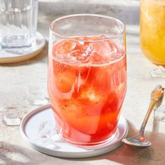 a glass filled with liquid sitting on top of a white plate next to a drink