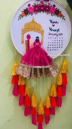 a wall hanging with a calendar on it and tassels attached to the clock