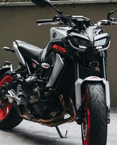 a black and silver motorcycle parked in front of a building with red rims on it's tires