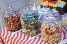 three jars filled with food sitting on top of a red and white striped table cloth