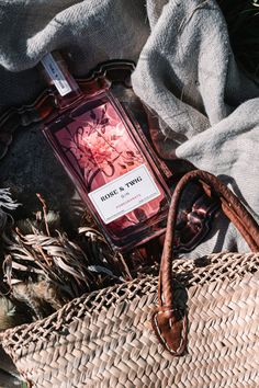 a bottle of perfume sitting on top of a basket next to a handbag and blanket