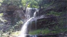 there is a waterfall in the middle of some rocks and trees with water cascading over it