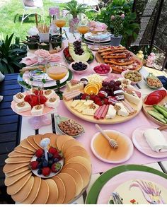 a table full of different types of food and drinks on it's tables outside