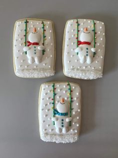 three decorated cookies sitting on top of a white table next to each other with frosting